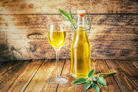Selbstgemachter Salbeisirup in einer Glasflasche mit Bügelverschluss und einem gefüllten Glas auf rustikalem Holztisch