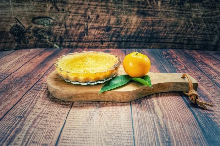 Calamondin-Tartelette mit frischer Calamondin auf einem Holzbrett