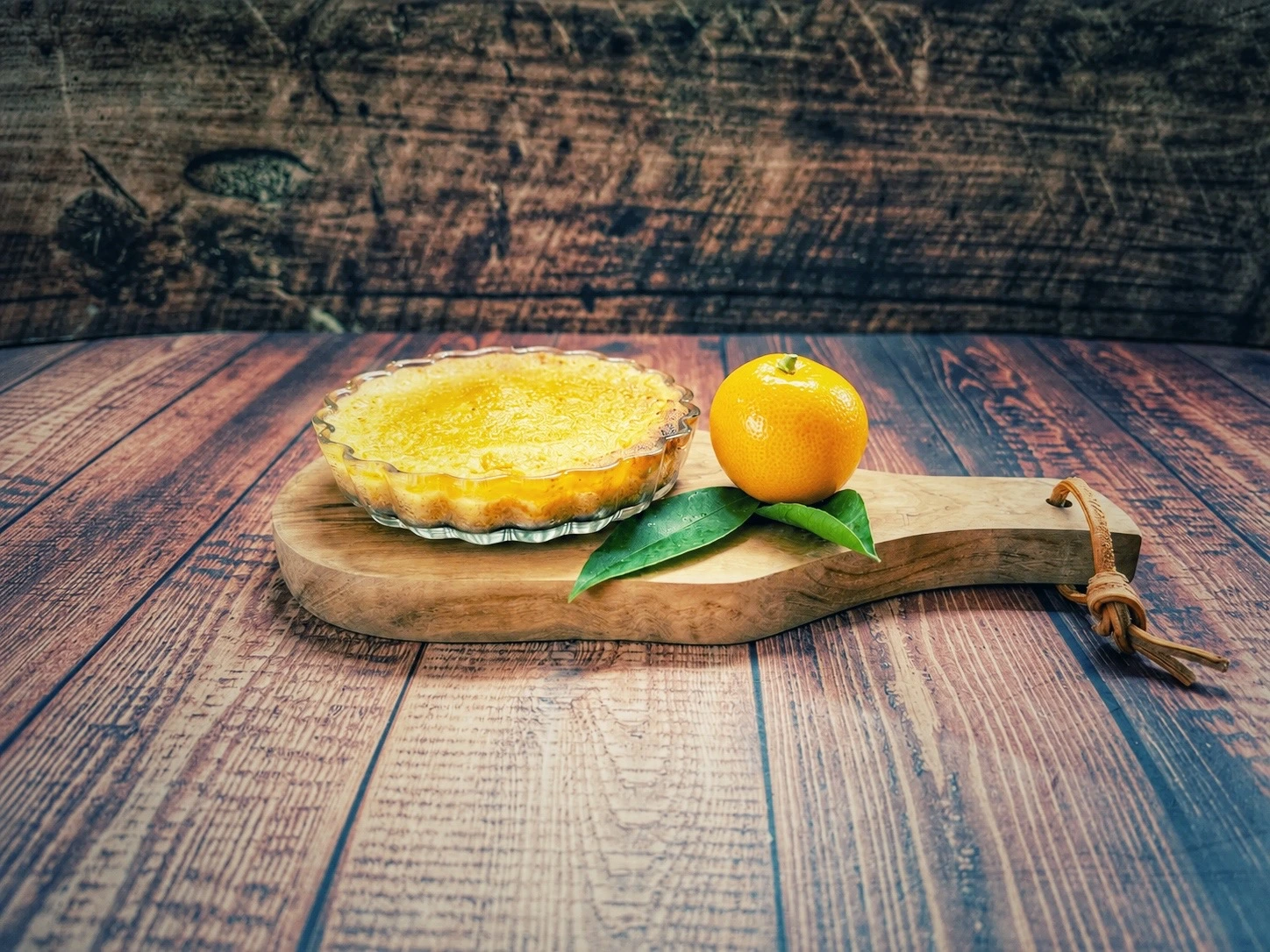 Calamondin-Tartelette mit frischer Calamondin auf einem Holzbrett