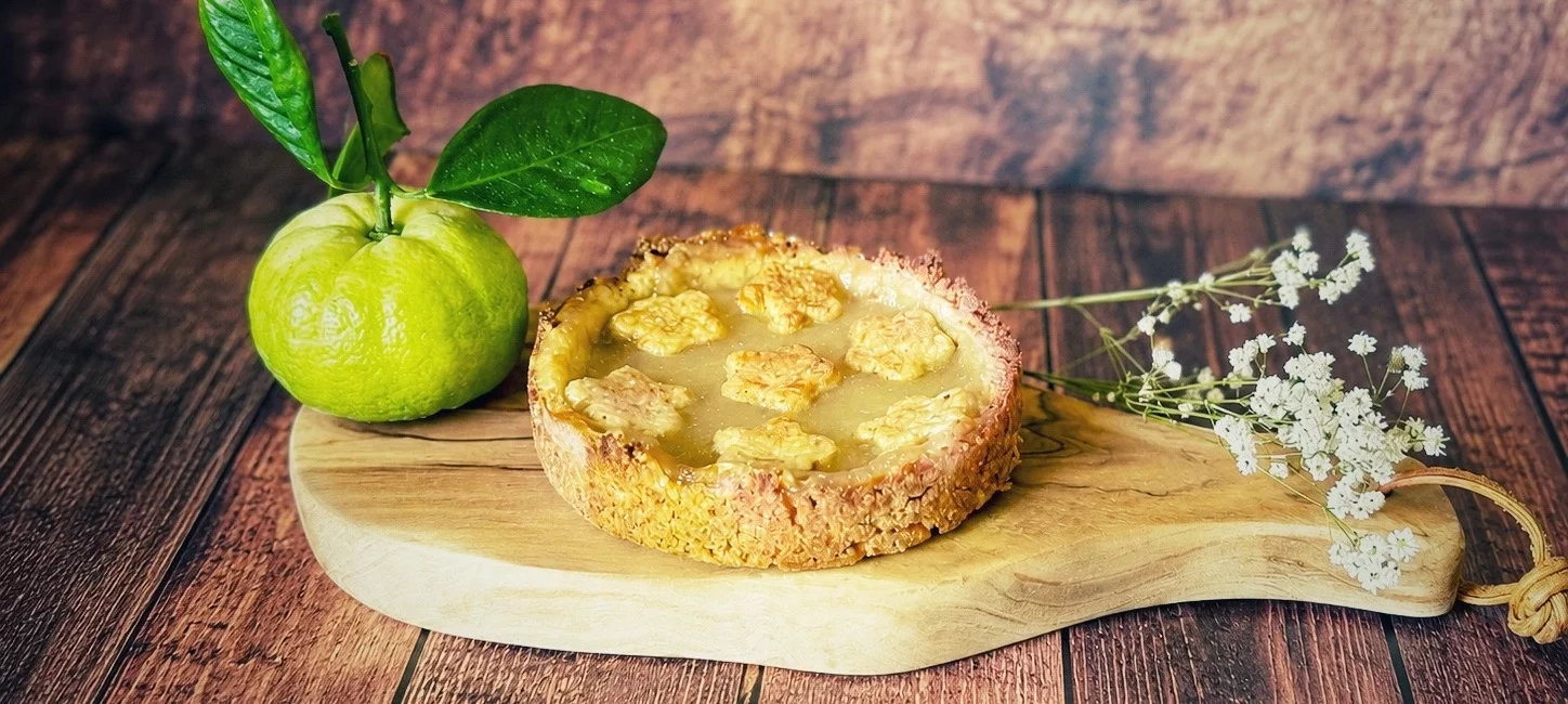 Pursha-Limetten-Tarte mit selbstgemachtem Pursha-Limetten-Curd auf einem Holzbrett mit frischen Pursha-Limetten