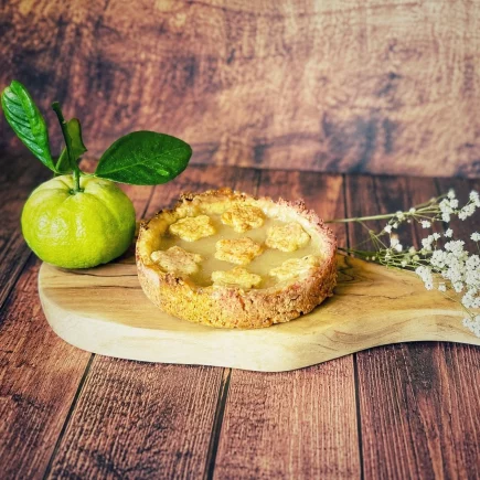 Pursha-Limetten-Tarte mit selbstgemachtem Pursha-Limetten-Curd auf einem Holzbrett mit frischen Pursha-Limetten