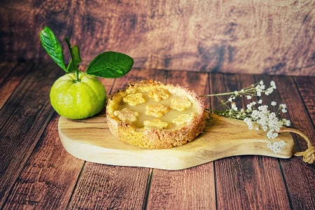 Pursha-Limetten-Tarte mit selbstgemachtem Pursha-Limetten-Curd auf einem Holzbrett mit frischen Pursha-Limetten