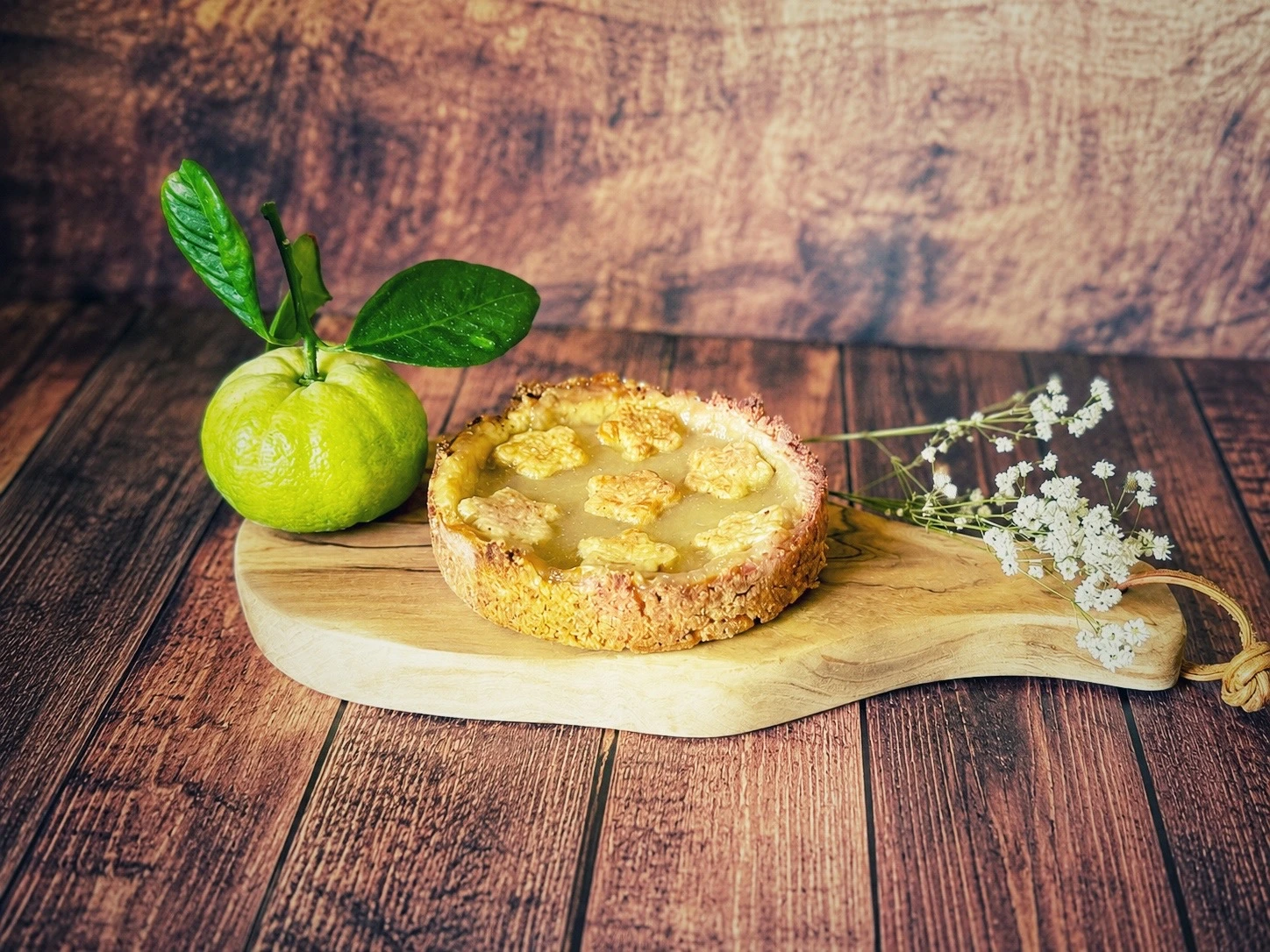 Pursha-Limetten-Tarte mit selbstgemachtem Pursha-Limetten-Curd auf einem Holzbrett mit frischen Pursha-Limetten