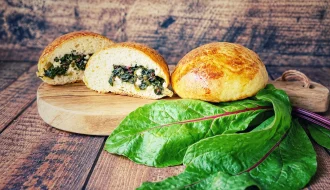Gef&uuml;llte Br&ouml;tchen mit Rote-Bete-Bl&auml;ttern und Feta auf einem Holzbrett