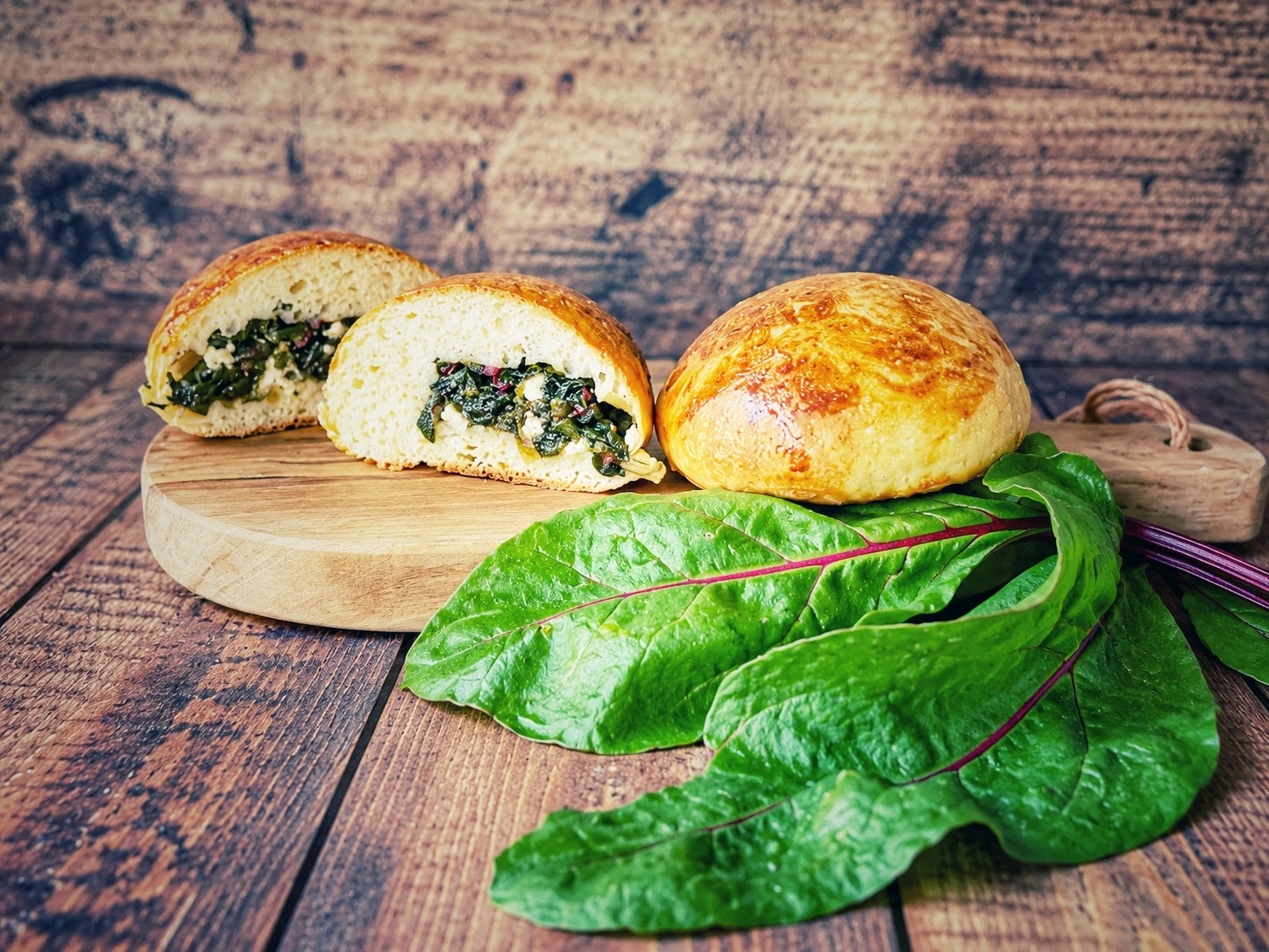 Gefüllte Brötchen mit Rote-Bete-Blättern und Feta auf einem Holzbrett